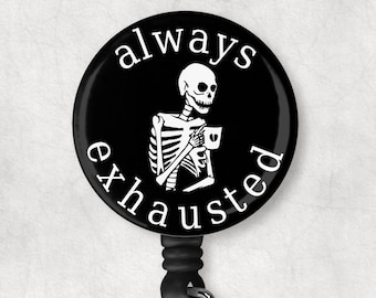 May include: Black and white retractable badge holder with a round button featuring a skeleton holding a coffee cup and the text "always exhausted".
