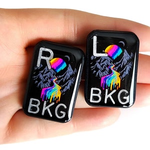 May include: Two black resin keycaps with a mountain and rainbow design. The keycaps are labeled "R BKG" and "L BKG".