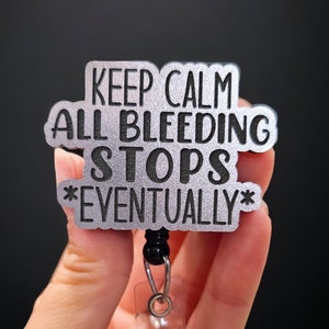 May include: Silver metal badge holder with a black retractable cord. The badge reads "Keep Calm All Bleeding Stops *Eventually*"