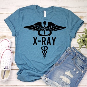 May include: A teal blue t-shirt with a black graphic of a medical symbol with wings and the text "X-RAY".