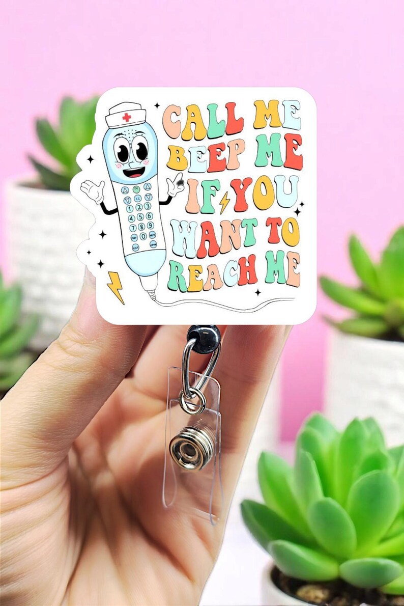 May include: A white badge reel with a retro-style telephone graphic and the text "CALL ME BEEP ME IF YOU WANT TO REACH ME." The badge reel has a clear plastic holder and a retractable cord.