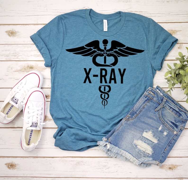 May include: A teal blue t-shirt with a black graphic of a medical symbol with wings and the text "X-RAY".
