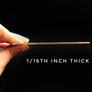 K&ouml;nnte beinhalten: Eine Nahaufnahme einer durchsichtigen Acrylplatte, die von einer Hand gehalten wird und die Dicke des Materials zeigt. Der Text "1/16TH INCH THICK" ist unter der Platte gedruckt.