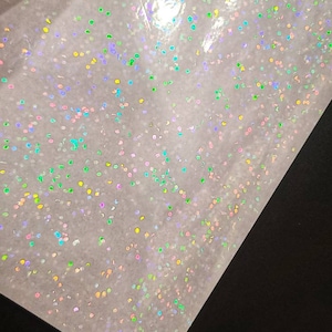 May include: A sheet of iridescent holographic vinyl with a scattered pattern of small, colorful dots.