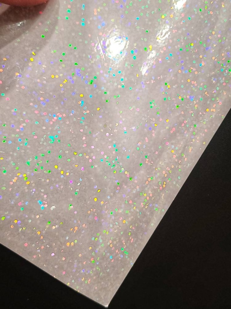 May include: A sheet of iridescent holographic vinyl with a scattered pattern of small, colorful dots.