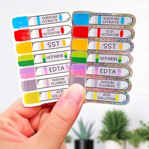 May include: A set of colorful sticker decals featuring labels for blood collection tubes. Each label is a different color and has text such as "Sodium Citrate", "Clot Activator", and "EDTA". The stickers have a glittery border.