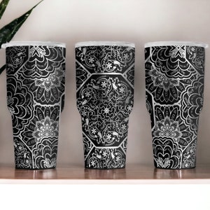 May include: Three black and silver stainless steel tumblers with a white mandala pattern.