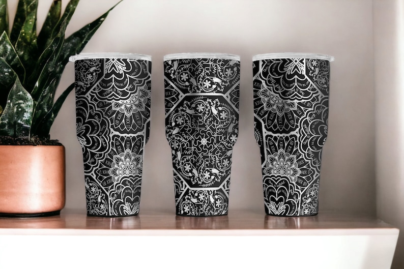 May include: Three black and silver stainless steel tumblers with a white mandala pattern.