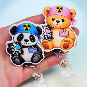 May include: Two cartoon badge reels featuring a panda and a teddy bear, each holding an X-ray image. The panda wears a blue bandana, and the bear wears a pink one. Both have an X-ray symbol and the word "XRAY".