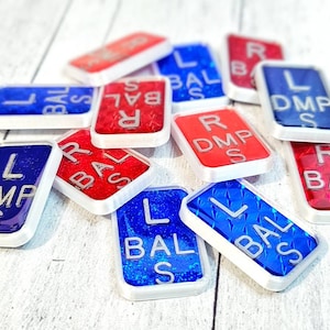 May include: A collection of red and blue eye chart letter tiles with white borders. The tiles have different letters and abbreviations, including "L", "R", "BAL", "DMP", and "S".