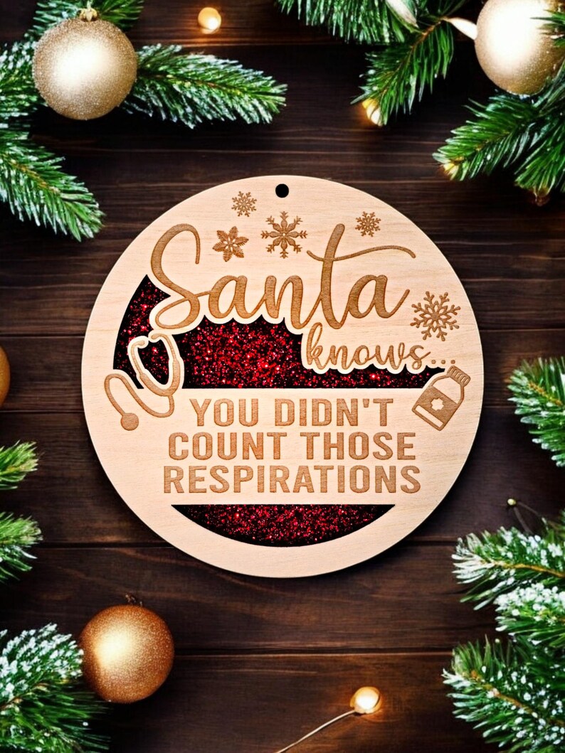 May include: A round wooden Christmas ornament with the words "Santa knows... You didn't count those respirations." The ornament has a red glitter center and snowflake and medical symbol designs. The ornament is surrounded by Christmas decorations.