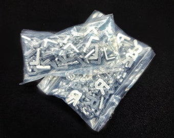May include: Two clear plastic bags filled with silver metal letter beads. One bag contains the letter "L" and the other bag contains the letter "R".