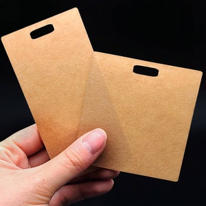 May include: Two brown cardboard tags with a hole punched in the top center of each tag.