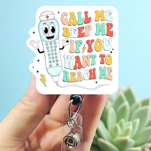 May include: A white and square badge reel with a cartoon telephone character wearing a nurse's hat. The text on the badge reel says "CALL ME BEEP ME IF YOU WANT TO REACH ME" in colorful retro lettering.
