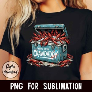 Puede incluir: Camiseta negra con un dise&ntilde;o de nevera azul llena de cangrejos rojos y hielo. El texto "WHO'S YOUR...CRAWADDY" est&aacute; en la nevera. Tambi&eacute;n se ven las palabras "Digital download" y "PNG FOR SUBLIMATION".