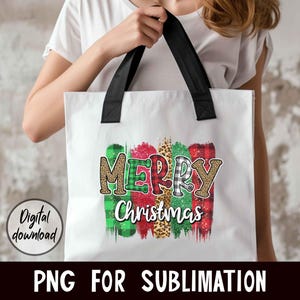 May include: White tote bag with black handles and a colorful "Merry Christmas" design featuring green, red, black, and white plaid patterns, leopard print, and glitter accents.