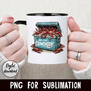 Puede incluir: Taza de cer&aacute;mica blanca con asa y borde negros. La taza presenta un gr&aacute;fico de nevera azul llena de cangrejos rojos y el texto "Who's your Crawdaddy". Tambi&eacute;n son visibles las palabras "Digital download".