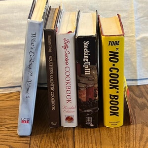 May include: A collection of five cookbooks with various titles, including "What's Cooking?? Volume 2", "Southern Country Cookbook", "Betty Crocker's Cookbook", "Stocking Up III", and "'NO-COOK' BOOK".