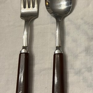 May include: A set of brown-handled silverware, including a fork and a spoon. The silverware is made of stainless steel and has a polished finish.