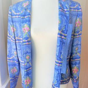 Puede incluir: Una chaqueta azul claro con un estampado floral con rosas rosas y un dise&ntilde;o paisley. La chaqueta tiene mangas largas y un cierre de un solo bot&oacute;n.