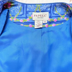 Puede incluir: Una chaqueta de seda azul con un forro de estampado floral. La etiqueta dice "Papell Petite" y "14P".