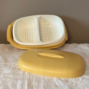 May include: A yellow two-tiered steamer with a lid. The top tier has two compartments with holes for steaming food. The bottom tier is solid.
