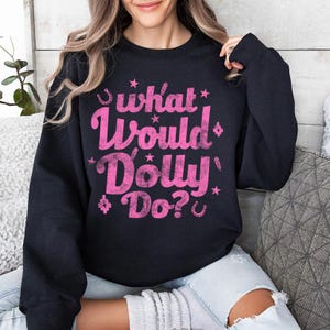 May include: Black sweatshirt with a pink graphic that says "What Would Dolly Do?" with stars and horseshoes around the text.