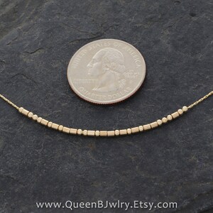 Coin with gold morse code necklace to show scale. www.queenbjwlry.etsy.com