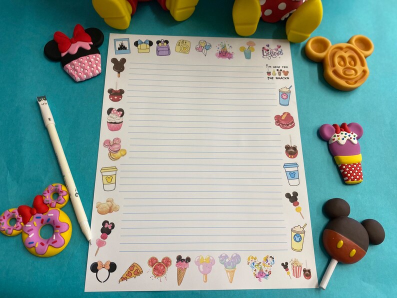 May include: A white sheet of paper with blue lines and a variety of colorful cartoon images of food and characters. The text "I'm here for the snacks" is printed on the paper.