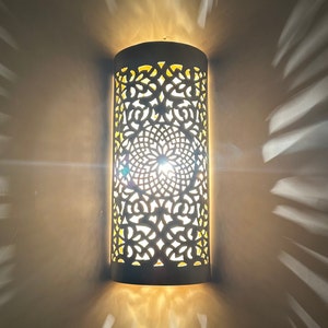 May include: White ceramic wall sconce with a intricate, lacy design. The sconce is illuminated from within, casting a warm glow.