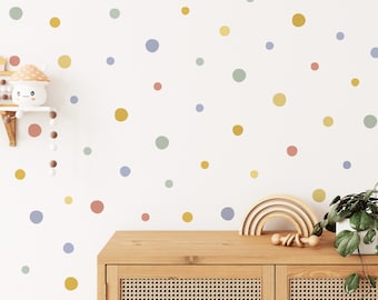 May include: A white wall with a colourful polka dot pattern in shades of blue, yellow, and pink. The wall is decorated with a rainbow wooden arch and a small wooden toy.
