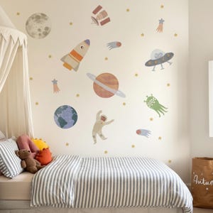 May include: A child's bedroom decorated with space-themed wall decals. The decals feature a moon, planets, rockets, an astronaut, and stars. The bed has a striped duvet cover and pillows. A teddy bear and decorative pillows are on the bed.