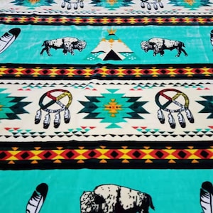 Puede incluir: Una manta de tiro turquesa y crema con un diseño nativo americano que presenta búfalos, plumas y patrones geométricos.