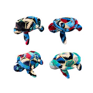 Pode incluir: Quatro brinquedos de pelúcia de tartaruga com desenhos de concha de patchwork em várias cores, incluindo azul, vermelho, preto e verde. As tartarugas têm apêndices semelhantes a barbatanas.