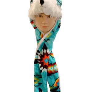 May include: A turquoise blue fleece hat with a white wolf face and ears. The hat has a matching scarf with a colorful geometric pattern.