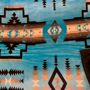 May include: A blue and black patterned throw blanket with a geometric design. The blanket features a diamond shape in the center with a smaller diamond inside. The blanket is made of a soft, plush material.