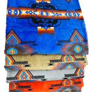 Puede incluir: Una pila de seis toallas coloridas con un patrón geométrico de inspiración suroeste. Las toallas son en tonos de azul, marrón, gris, naranja y turquesa.