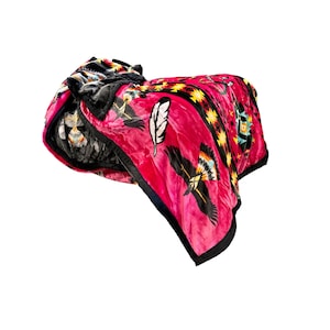 May include: A pink and black fleece blanket with a Native American inspired design featuring feathers and geometric patterns.