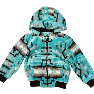 May include: A plush, turquoise hooded jacket featuring a black, white, and gray geometric pattern. The jacket has a full-length front zipper, long sleeves with black ribbed cuffs, and a black ribbed hem. The soft, fuzzy texture covers the entire exterior.