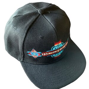 May include: A black baseball cap with a colorful embroidered design featuring geometric shapes and patterns. The design is centered on the front of the cap.