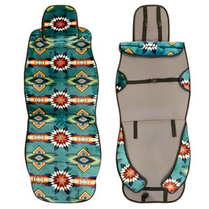 Op de afbeelding: Een autostoelhoes met een teal, oranje en zwart patroon en een grijze achterkant. De hoes heeft een hoofdsteun en een band om hem aan de stoel te bevestigen.