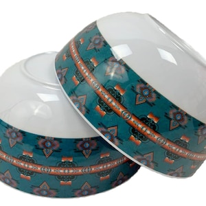 May include: Two white ceramic bowls with a teal, orange, and brown geometric pattern around the rim.