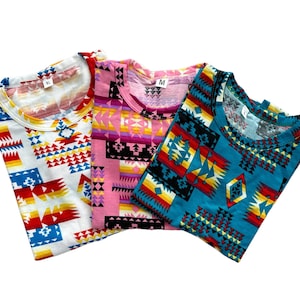 Puede incluir: Tres camisetas con un patrón geométrico en tonos de rojo, amarillo, azul y blanco. Las camisetas están hechas de una tela suave y cómoda y son perfectas para el uso diario.