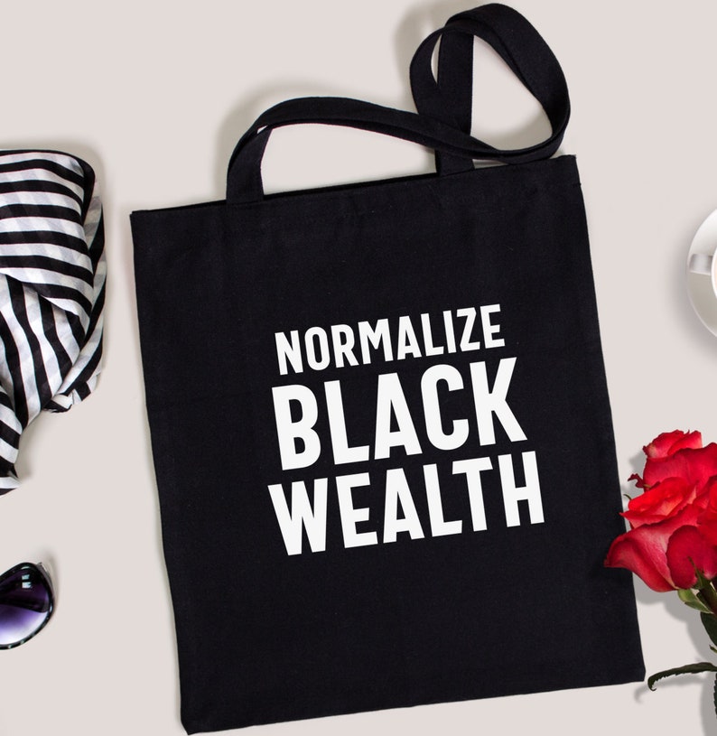 May include: Black tote bag with white text that reads "Normalize Black Wealth".