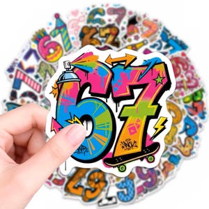 May include: A die-cut vinyl sticker featuring the number 67 in a vibrant graffiti style. The number 6 is blue with pink accents, and the number 7 is orange and yellow. A spray paint can and a skateboard are integrated into the design.