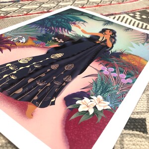 May include: A woman in a blue and gold patterned saree stands in a lush tropical garden. The saree has a floral design and is accented with gold dots. The woman is surrounded by green plants and flowers.