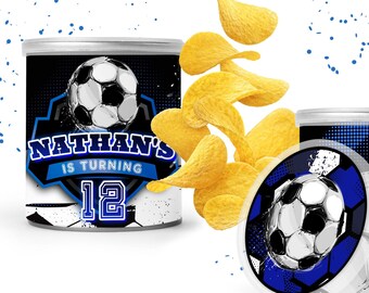 May include: A blue and white soccer-themed chip can with the text "Nathan's is turning 12". The can is decorated with a soccer ball and a blue and white striped pattern. The can is sitting on a white surface.