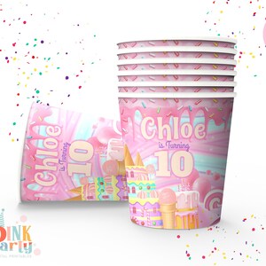 May include: Pink and white paper cups with a candy-themed design. The cups feature a pink and white swirl background with a castle, ice cream cones, and lollipops. The text "Chloe is turning 10" is printed on the cups.