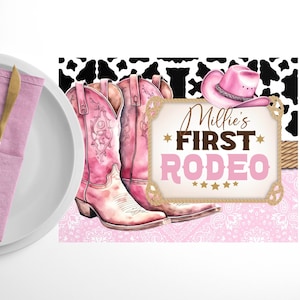 Puede incluir: Botas vaqueras rosas con un sombrero vaquero rosa y un cartel que dice "Millie's First Rodeo" sobre un fondo rosa y blanco con un patrón de vaca.