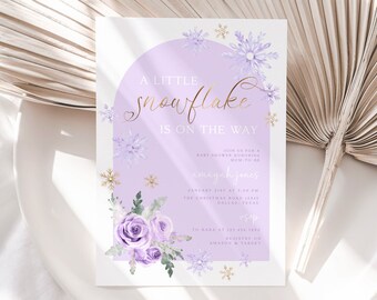 Op de afbeelding: Een paarse en gouden babyborrel uitnodiging met een sneeuwvlok ontwerp en de tekst "A Little Snowflake is on the Way". De uitnodiging bevat de datum, tijd en locatie van de borrel, evenals de naam van de aanstaande moeder, "Mayah Jones".